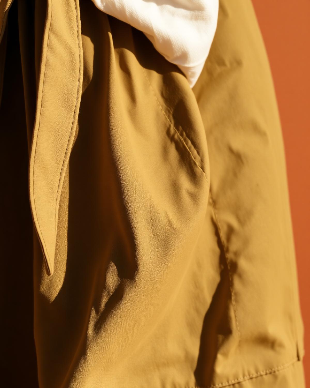 Macro detail of olive linen trousers drawstring tie and drape