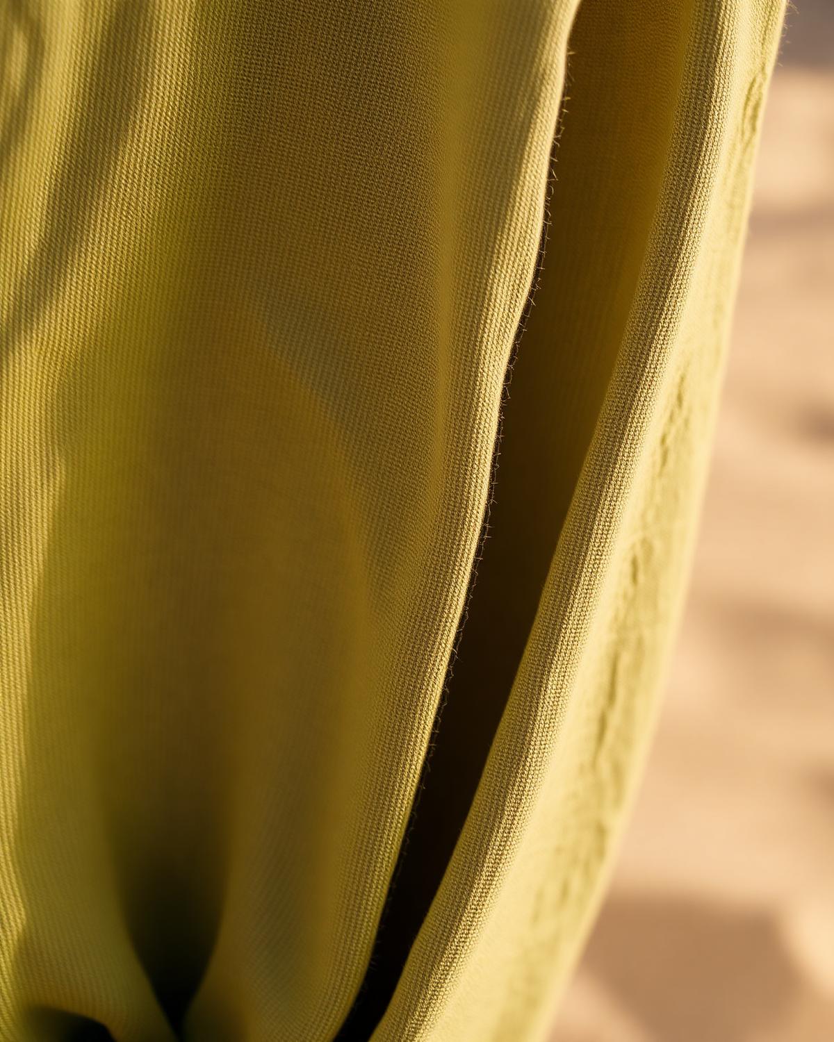 Macro detail of olive linen weave and hand-stitched hem
