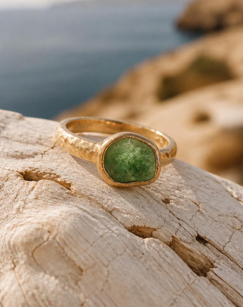 Hammered gold ring with a raw emerald on white driftwood
