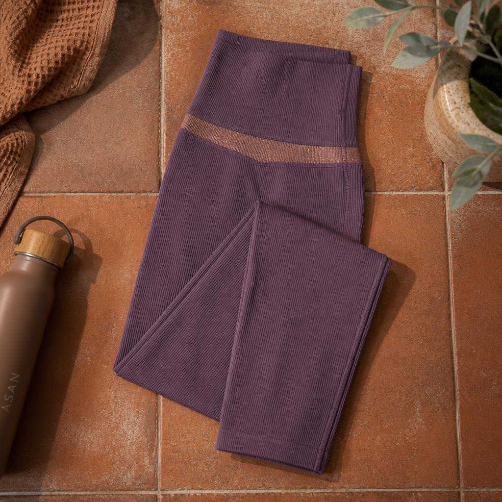 Muted amethyst ribbed yoga tights with bronze waistband, flat lay on terracotta tile