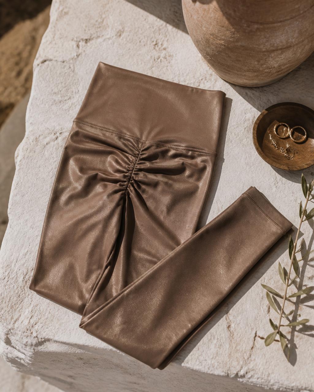 Burnished bronze seamless scrunch-back yoga tights, flat lay on stone