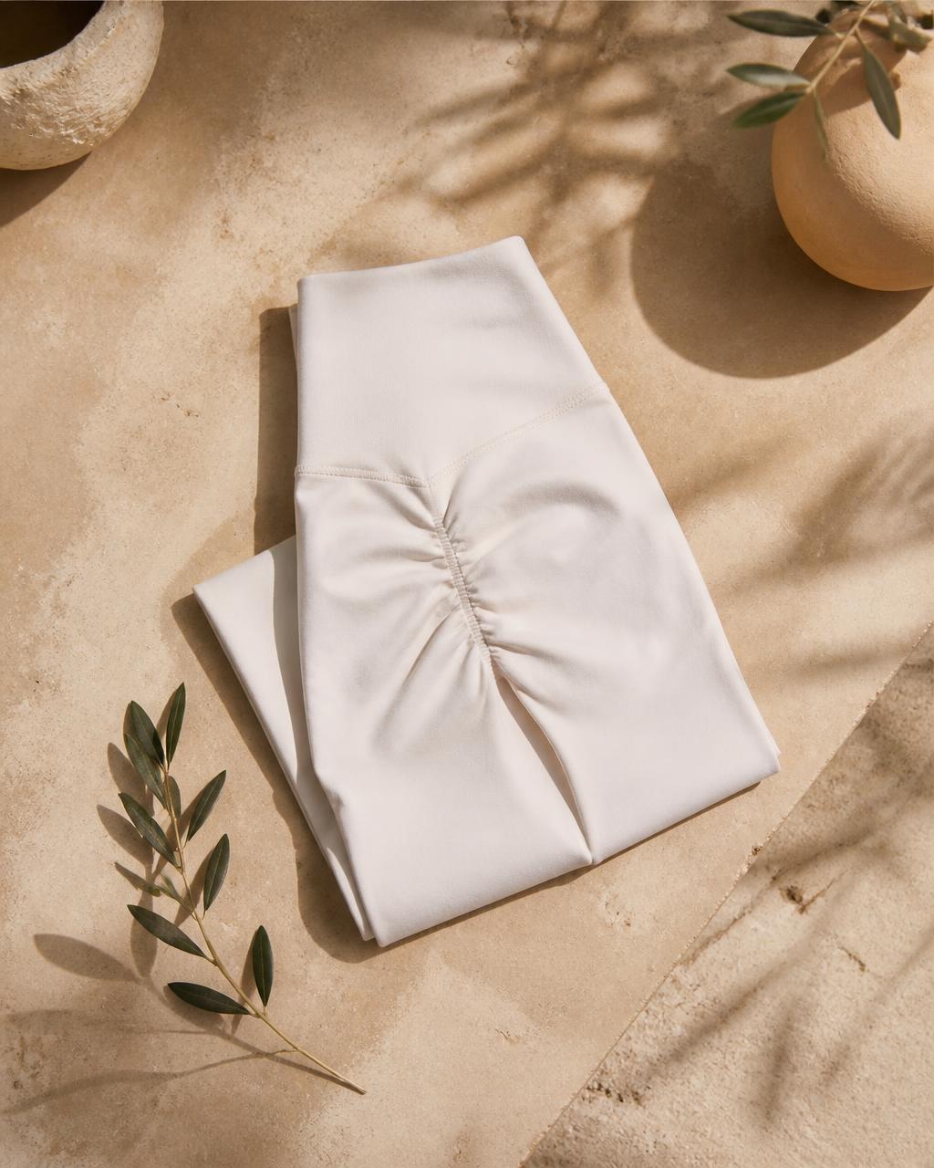 Chalk white seamless scrunch-back yoga tights, flat lay on sand stone