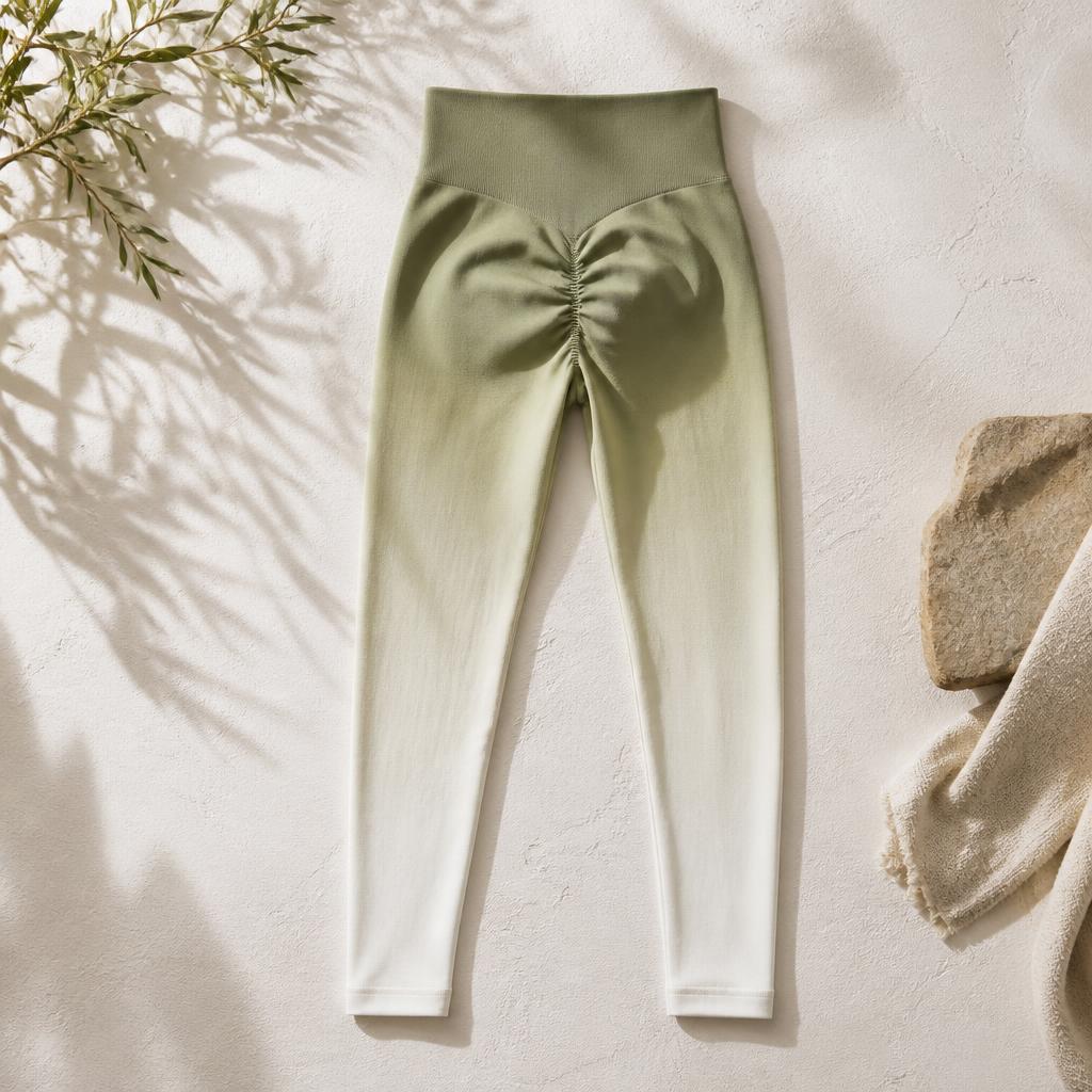 Ombré yoga tights fading from olive at the waist to chalk at the ankle, flat lay