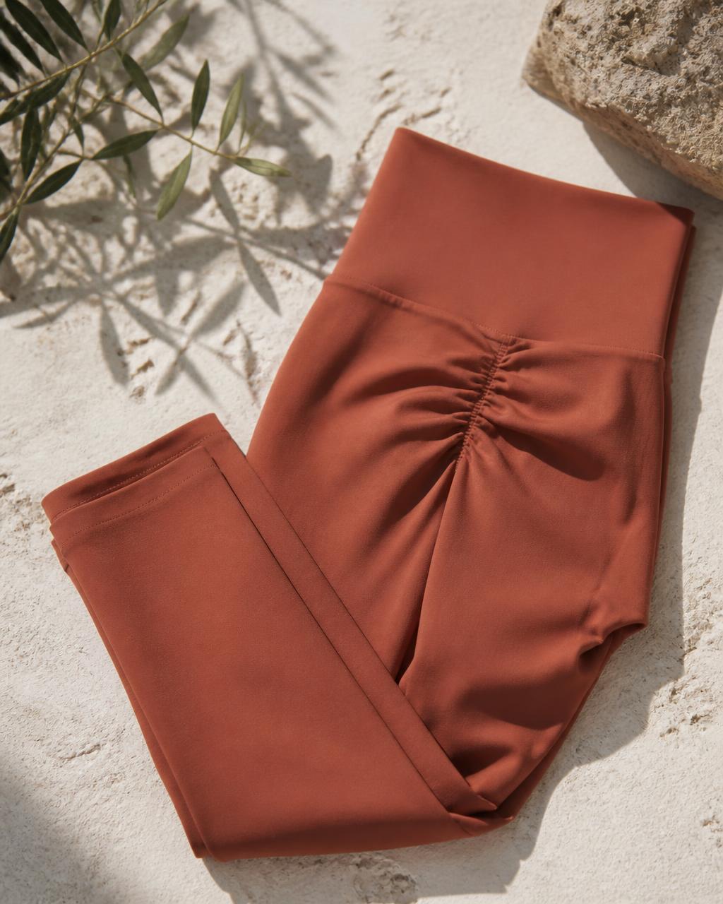 Terracotta seamless scrunch-back yoga leggings folded on sunlit stone